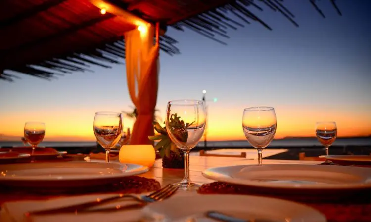 Mesa de restaurante turístico en la playa con copas, vasos, platos y cubertería  completa Photos